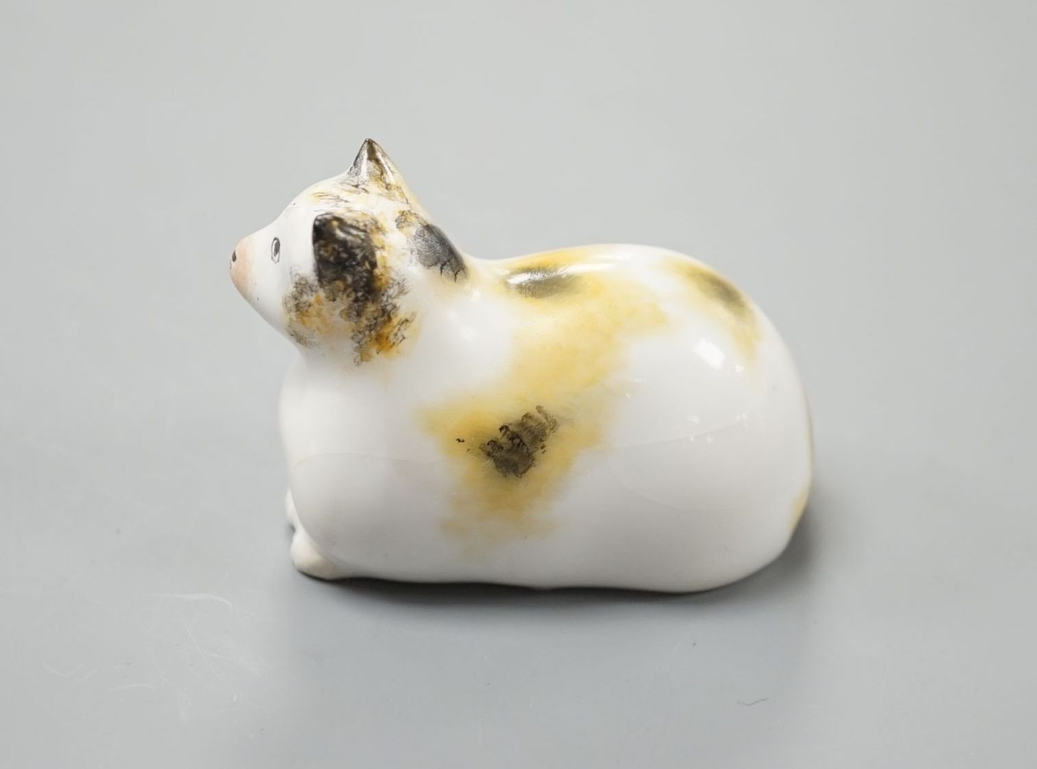 A rare Staffordshire porcelain figure of a recumbent cat, c.1835-50, with impossibly long tail, 6 cm long, Cf. Dennis G.Rice Cats in English porcelain, colour plate 54., Provenance: Dennis G.Rice collection